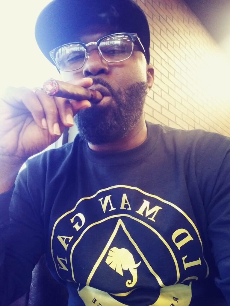 A man with a beard and glasses smoking a cigar.